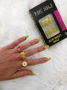 hand wearing cute smiley and daisy spring rings and bright yellow smiley press on nails