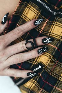 hand wearing witch press on nails with satanic symbols and runes and yellow checkered pants