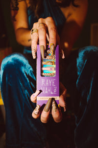 girl wearing and holding a box of brown and purple press on nails with crystals glued on