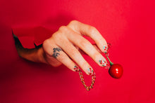 Load image into Gallery viewer, a hand with a flame tattoo bursting through red background holding a cherry wearing clear cute press on nails