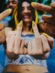 two people in 90s clothes giving the middle finger wearing yellow trippy smiley press on nails