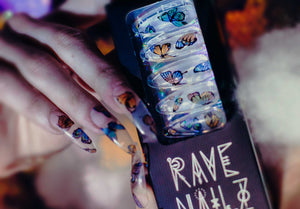 box of long stiletto clear press on nails with butterflies and a hand wearing the fake nails