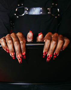 guy wearing press on nails that are red and black with silver metal pieces