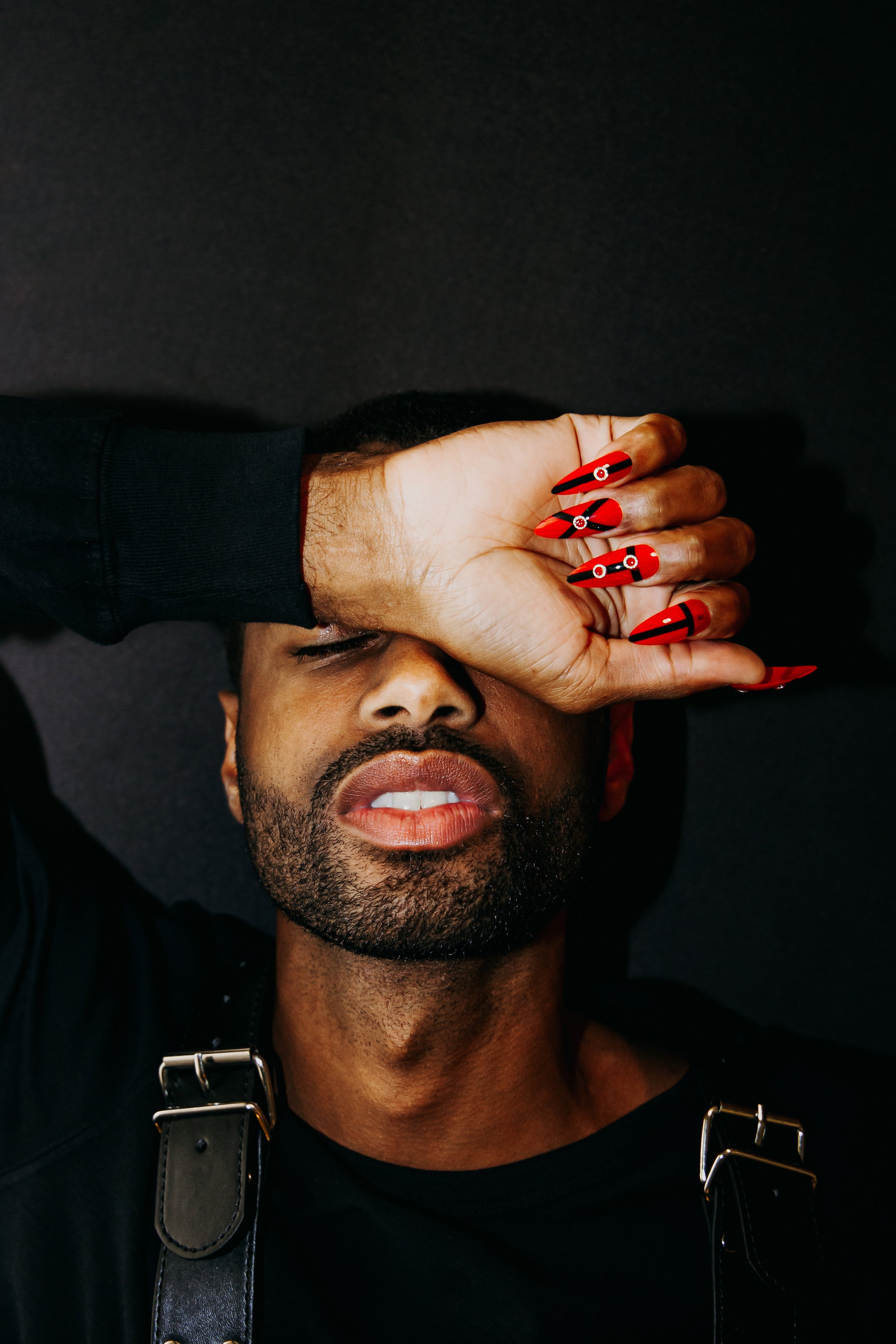 guy wearing black leather harness and red strappy press on nails