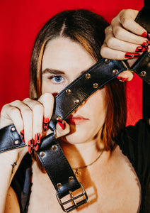 girl with blue eyes holding black leather strap wearing long red press on nails