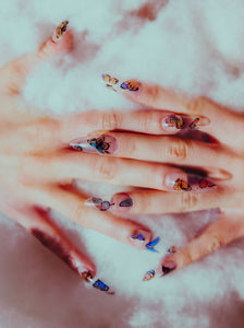 hands in the clouds wearing butterfly press on nails that are long and clear
