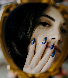 girl reflection wearing dark pointy press on nails with shiny gold sigils